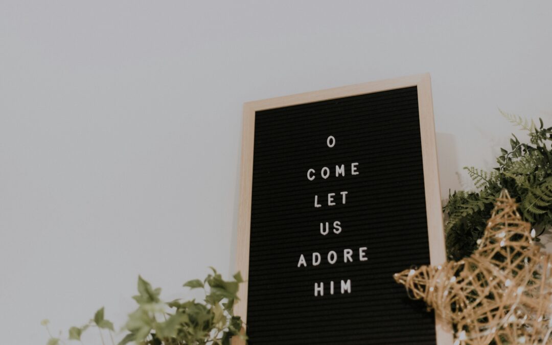 Bulletin board with the word "O come let us adore him."