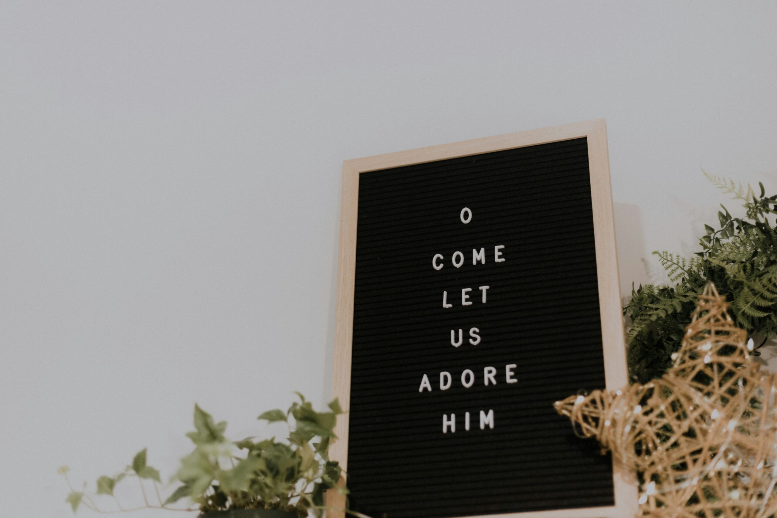 Bulletin board with the word "O come let us adore him."